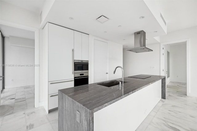 kitchen featuring a center island with sink, sink, white cabinetry, and island exhaust hood