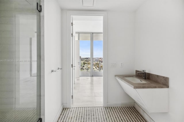 bathroom featuring a shower with door, tile patterned floors, expansive windows, and sink