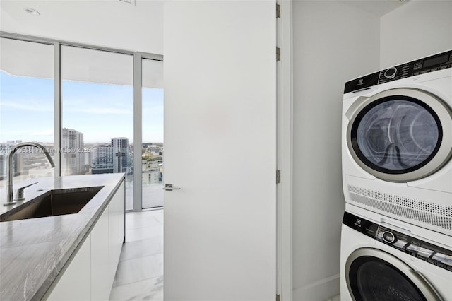 clothes washing area featuring stacked washer and clothes dryer and sink