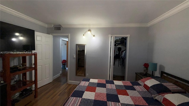 bedroom with a walk in closet, dark hardwood / wood-style floors, a closet, and crown molding