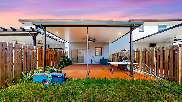 back house at dusk with a patio, central AC, and ceiling fan