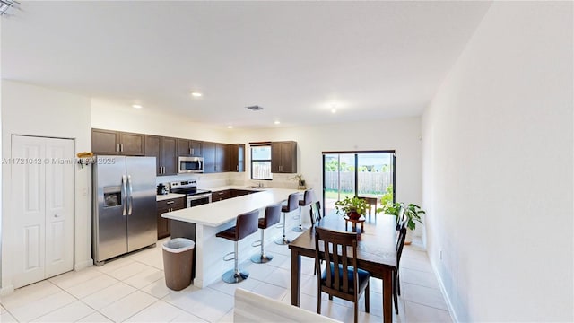 kitchen featuring light tile patterned floors, dark brown cabinetry, stainless steel appliances, and sink