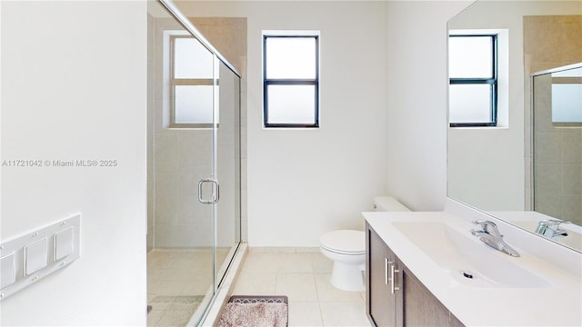 bathroom with tile patterned floors, a wealth of natural light, vanity, and toilet