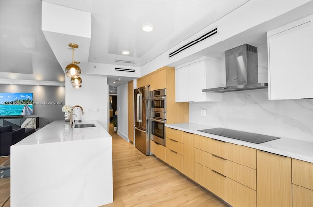 kitchen featuring white cabinetry, sink, wall chimney exhaust hood, stainless steel appliances, and decorative light fixtures