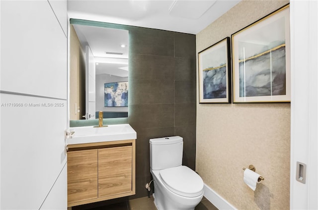 bathroom with vanity, tile walls, and toilet