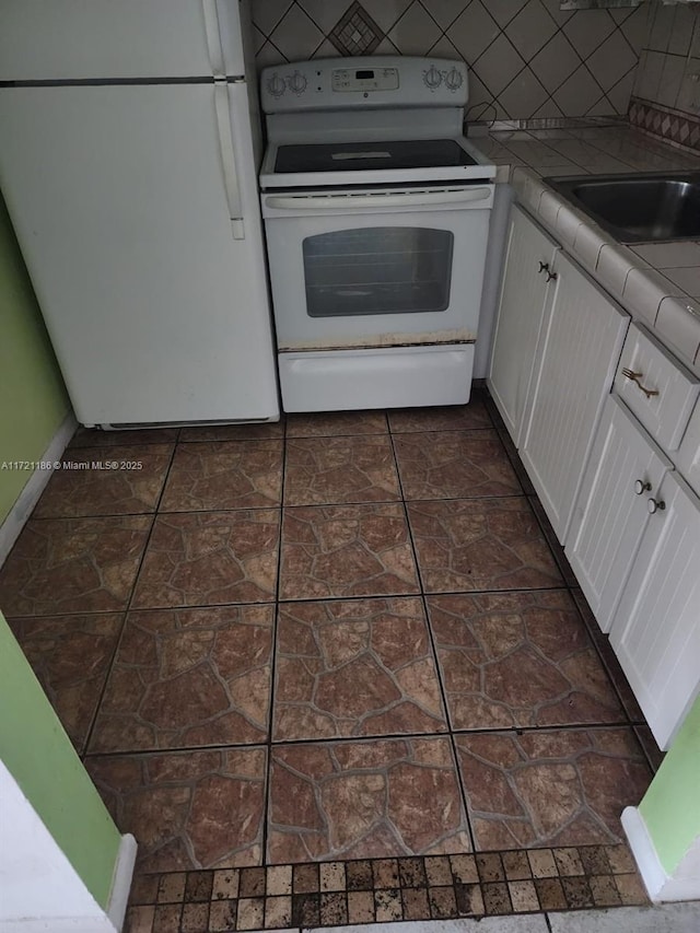 kitchen with tile countertops, white appliances, dark tile patterned flooring, tasteful backsplash, and white cabinetry