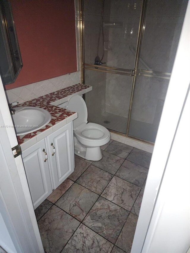 bathroom with vanity, a shower with shower door, and toilet