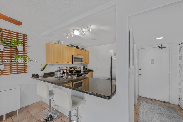 kitchen featuring kitchen peninsula, a breakfast bar, ceiling fan, light tile patterned floors, and white refrigerator