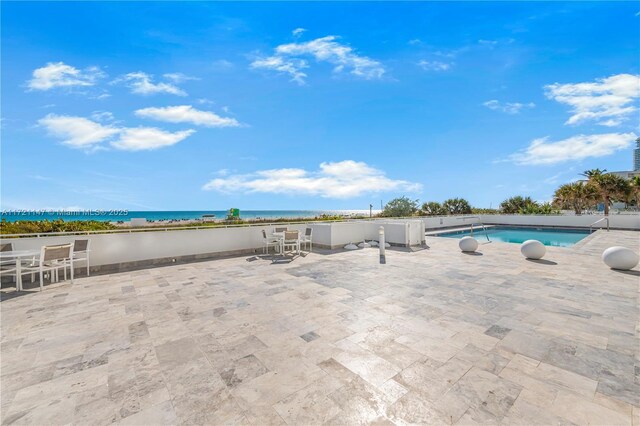 view of swimming pool featuring a patio, outdoor dining area, a water view, and a fenced in pool