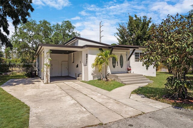 571 Raven Ave, Miami Springs, FL 33166 - view of front facade with a front lawn, stucco siding, driveway, and an attached carport