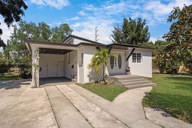 571 Raven Ave, Miami Springs, FL 33166 - view of front of property with a front lawn, stucco siding, driveway, and an attached carport