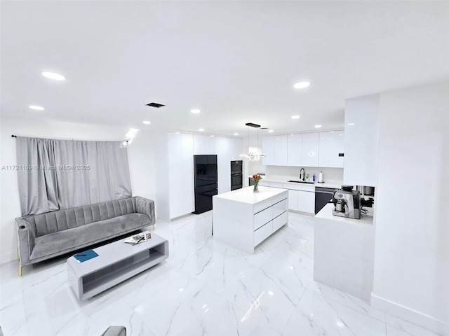 kitchen with white cabinets, black appliances, pendant lighting, a center island, and sink