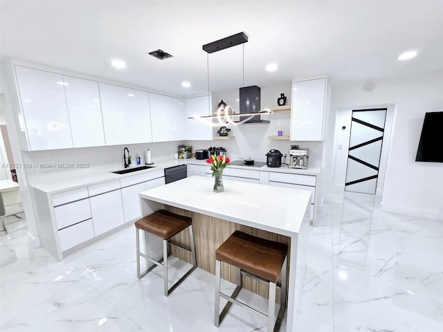 kitchen with sink, white cabinets, a breakfast bar area, and hanging light fixtures