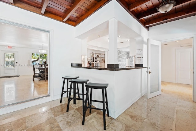 kitchen with beamed ceiling, wood ceiling, kitchen peninsula, and french doors