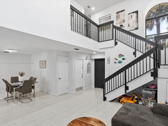 stairs with tile patterned floors and a high ceiling