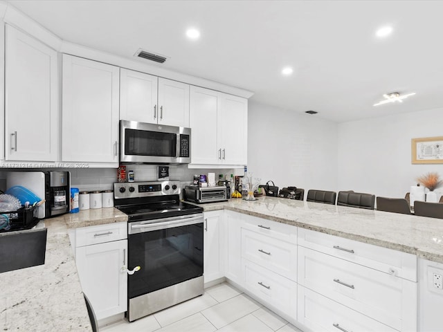 kitchen with light stone countertops, white cabinets, and appliances with stainless steel finishes