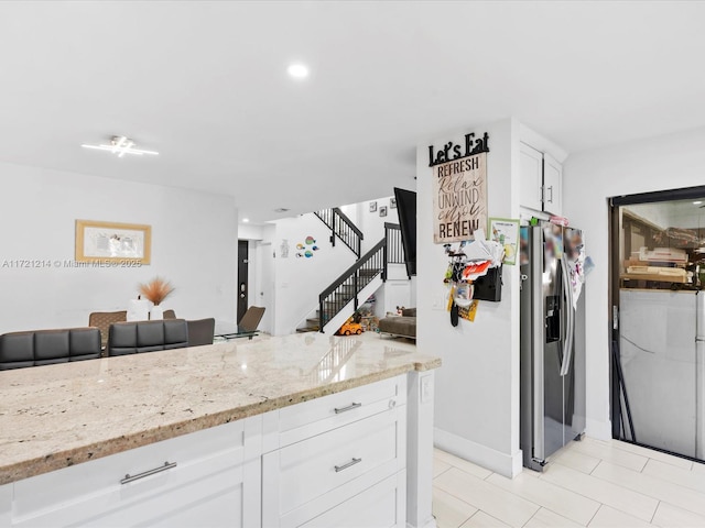 kitchen featuring white cabinetry, light stone counters, and stainless steel fridge with ice dispenser