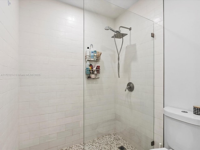 bathroom featuring tiled shower and toilet