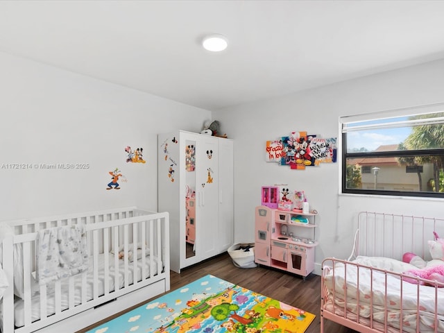 bedroom with dark wood-type flooring and a nursery area