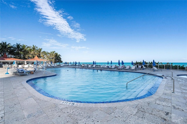 view of pool featuring a patio and a water view