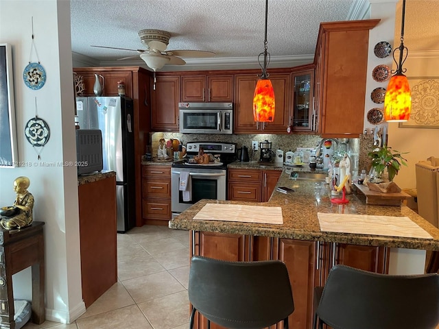 kitchen with kitchen peninsula, sink, decorative light fixtures, and appliances with stainless steel finishes