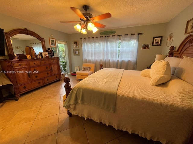 tiled bedroom with ceiling fan and a textured ceiling