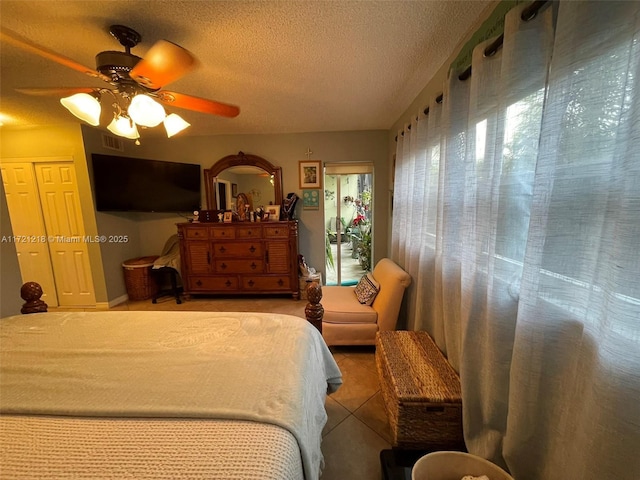 bedroom with a textured ceiling, tile patterned floors, and ceiling fan