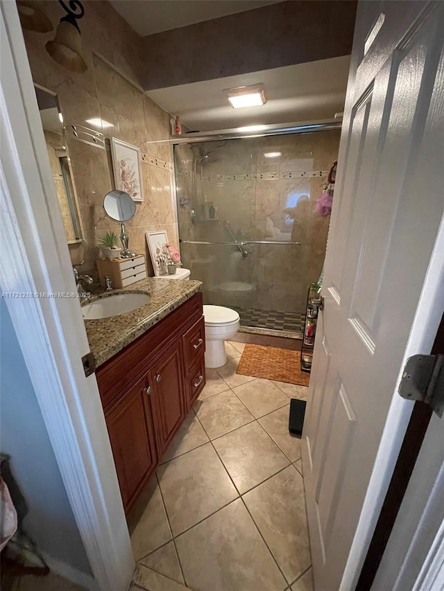 bathroom featuring tile patterned floors, an enclosed shower, vanity, tile walls, and toilet