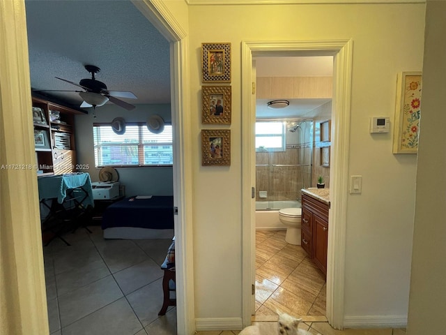 hallway featuring light tile patterned floors, a textured ceiling, and a wealth of natural light