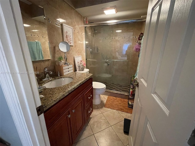 bathroom with an enclosed shower, vanity, toilet, and tile walls