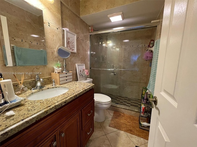 bathroom featuring vanity, tile walls, tile patterned flooring, toilet, and a shower with shower door