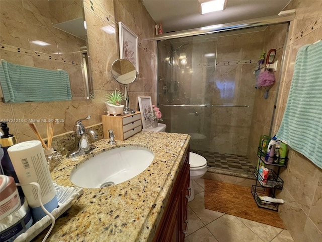 bathroom with walk in shower, tile patterned flooring, toilet, vanity, and tile walls