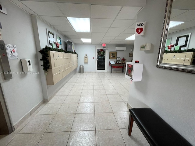 corridor featuring a paneled ceiling, a wall mounted AC, and a mail area