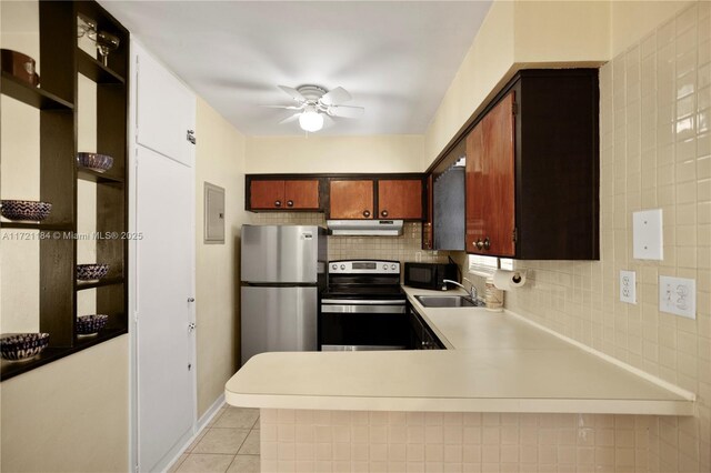 kitchen featuring ceiling fan, kitchen peninsula, decorative backsplash, light tile patterned flooring, and appliances with stainless steel finishes