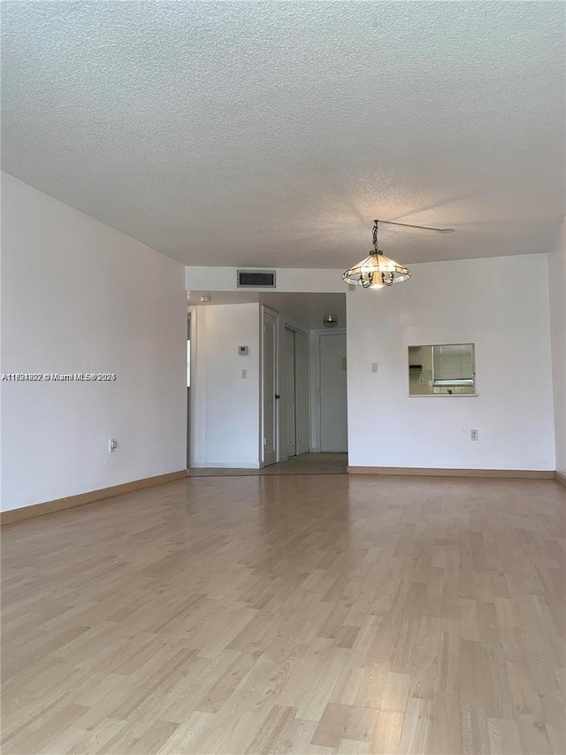 unfurnished room with light hardwood / wood-style flooring and a textured ceiling