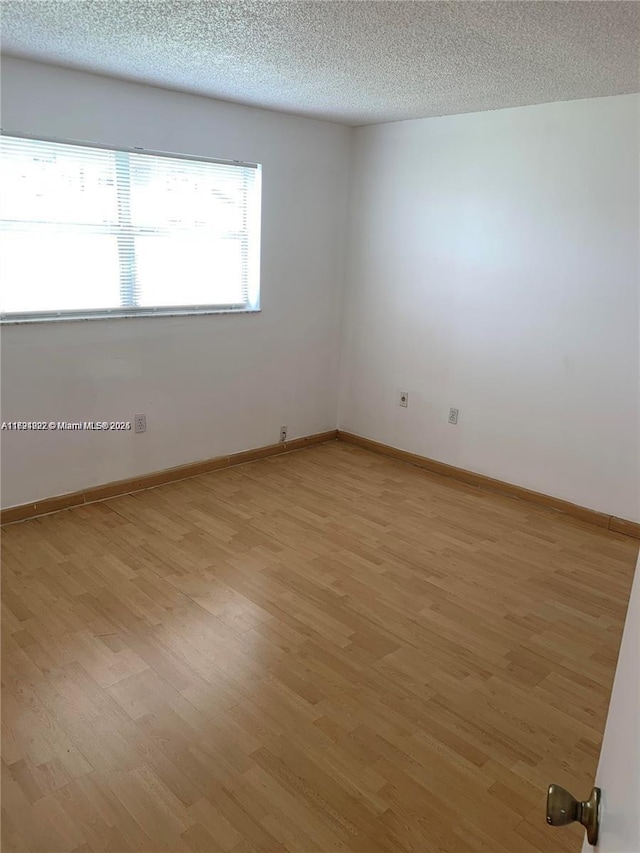 spare room with a textured ceiling and light wood-type flooring