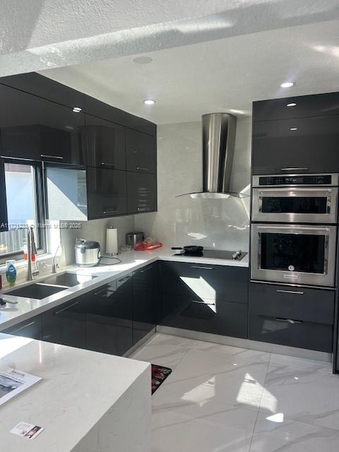 kitchen featuring stainless steel double oven, wall chimney range hood, sink, and black electric cooktop