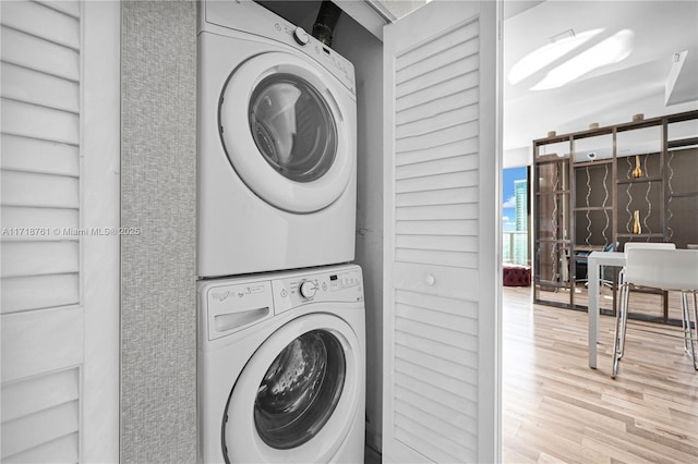 clothes washing area with stacked washer and clothes dryer and light hardwood / wood-style flooring