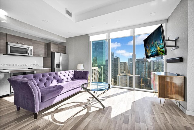 living room with light hardwood / wood-style floors and a wall of windows