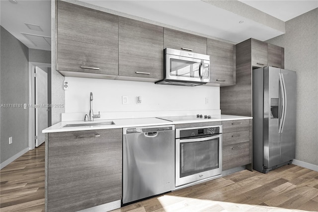 kitchen with appliances with stainless steel finishes, light hardwood / wood-style flooring, and sink