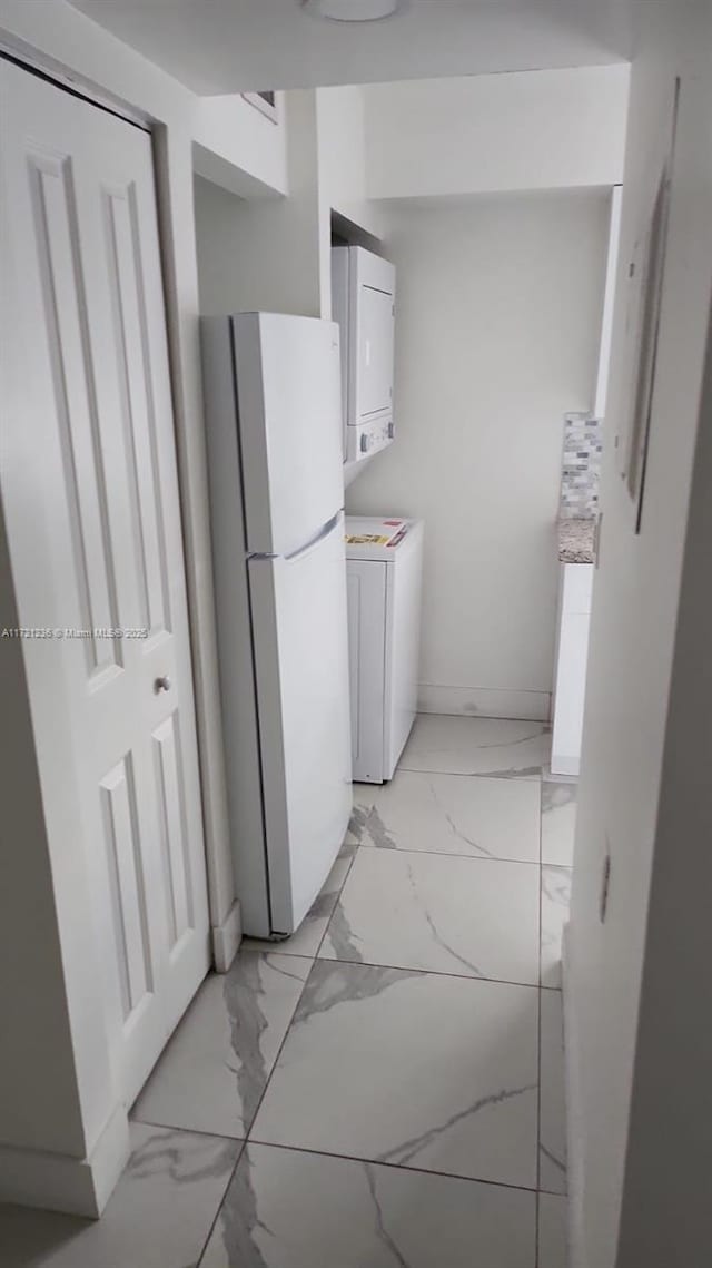 kitchen with white cabinets, white refrigerator, and stacked washer and dryer