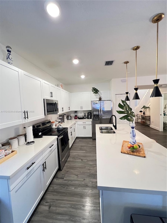 kitchen featuring white cabinetry, appliances with stainless steel finishes, sink, and pendant lighting