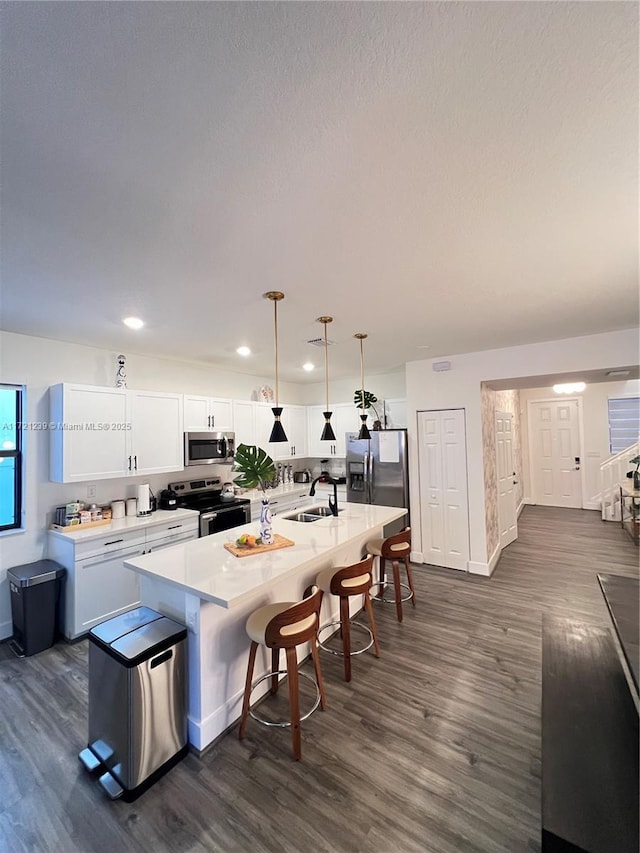 kitchen featuring sink, hanging light fixtures, stainless steel appliances, a kitchen breakfast bar, and white cabinets