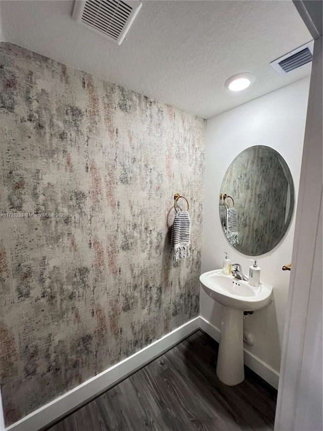 bathroom featuring wood-type flooring and a textured ceiling