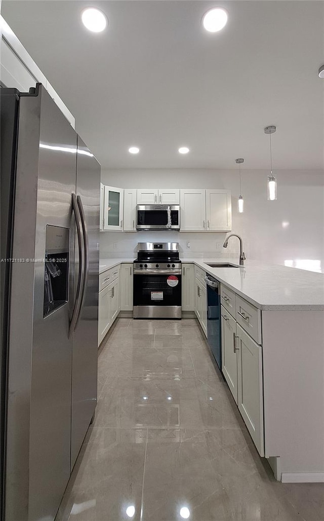 kitchen featuring pendant lighting, white cabinets, sink, appliances with stainless steel finishes, and kitchen peninsula