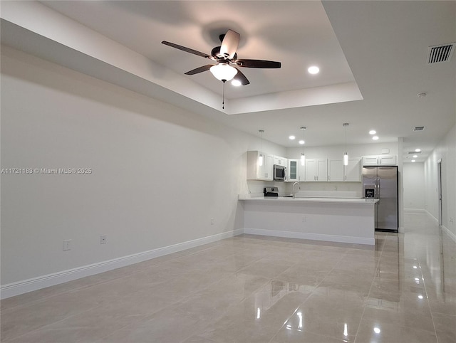 unfurnished living room with a tray ceiling, ceiling fan, and sink