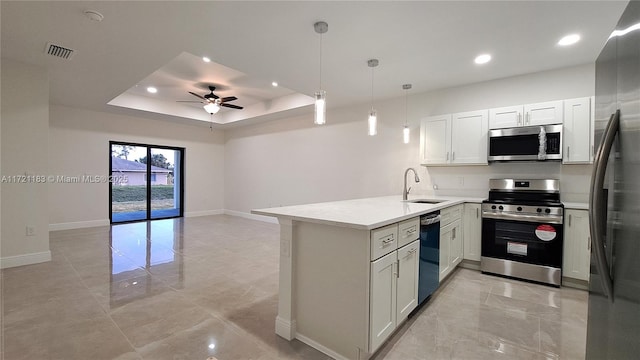 kitchen with kitchen peninsula, stainless steel appliances, a raised ceiling, decorative light fixtures, and white cabinets