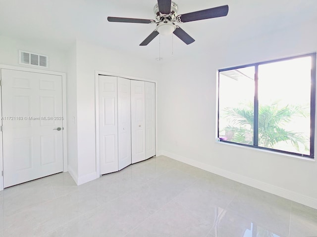 unfurnished bedroom with ceiling fan, light tile patterned floors, and a closet