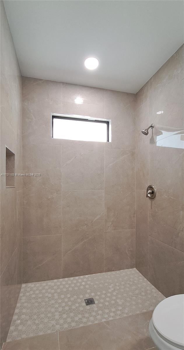 bathroom with tiled shower and toilet