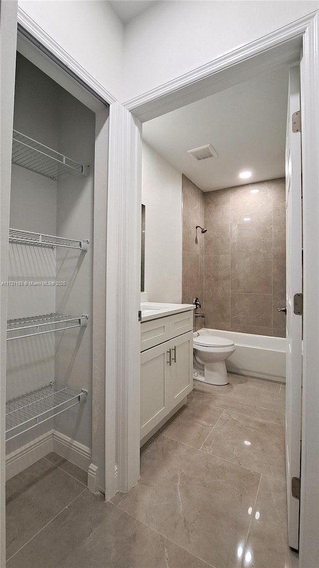 full bathroom with vanity, tiled shower / bath combo, and toilet